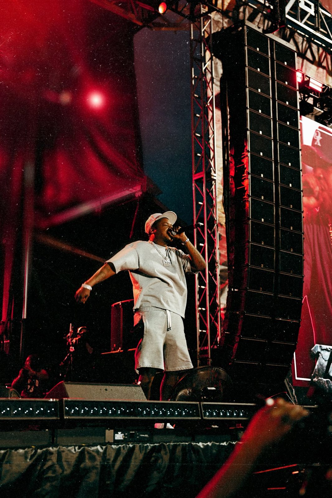 Artist performing on a festival stage under red lights