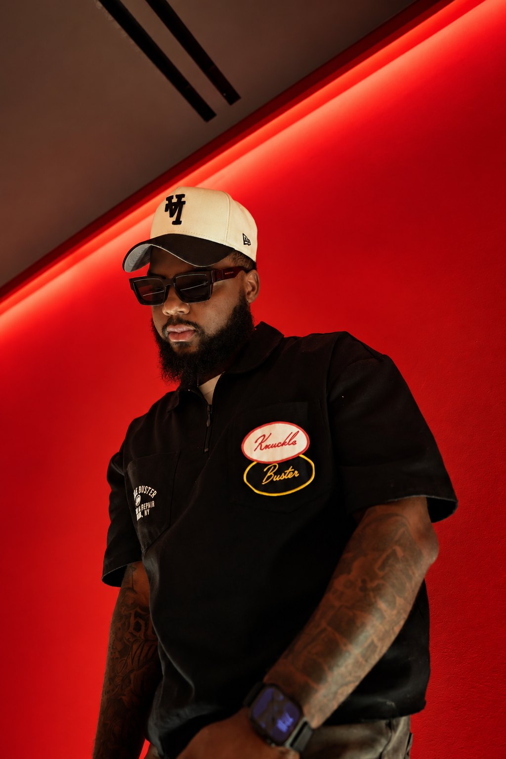 Ken, the photographer behind Kenframes, in a cap and sunglasses against a red wall