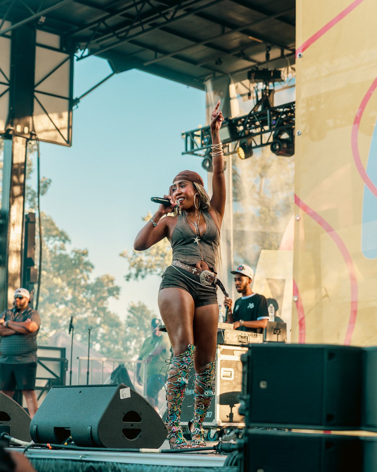 Performer with arm raised on an outdoor festival stage in daylight